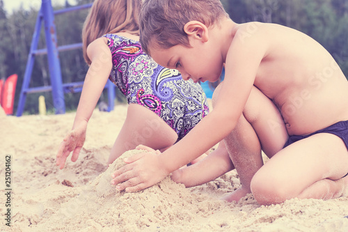 Group of litle cute kids makes sand castle at the beach