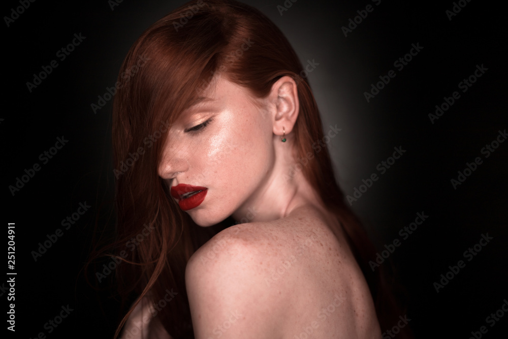 The portrait of a young redhead lady isolated over a black background The portrait of a young redhead lady isolated over a black background