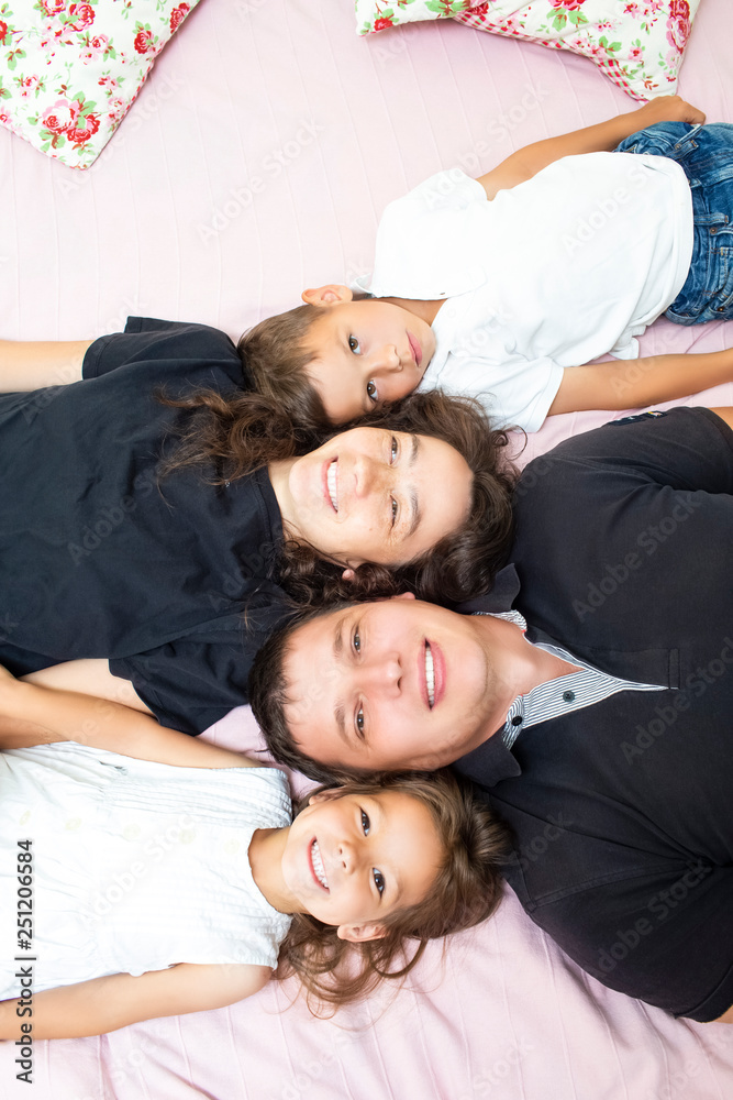 Family Values. Happy Caucasian Family of Four Having Fun While Lying on Sofa Indoors.