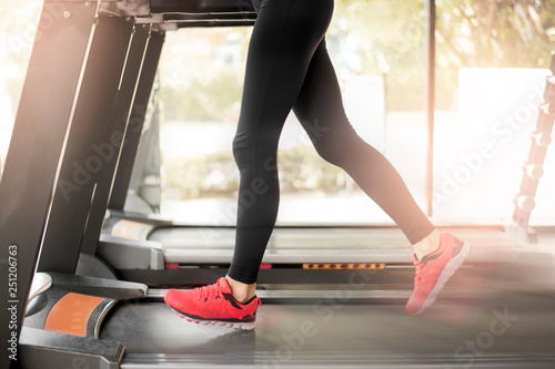 Close up of woman's muscular legs feet running on treadmill workout at fitness gym, Healthy lifestyle