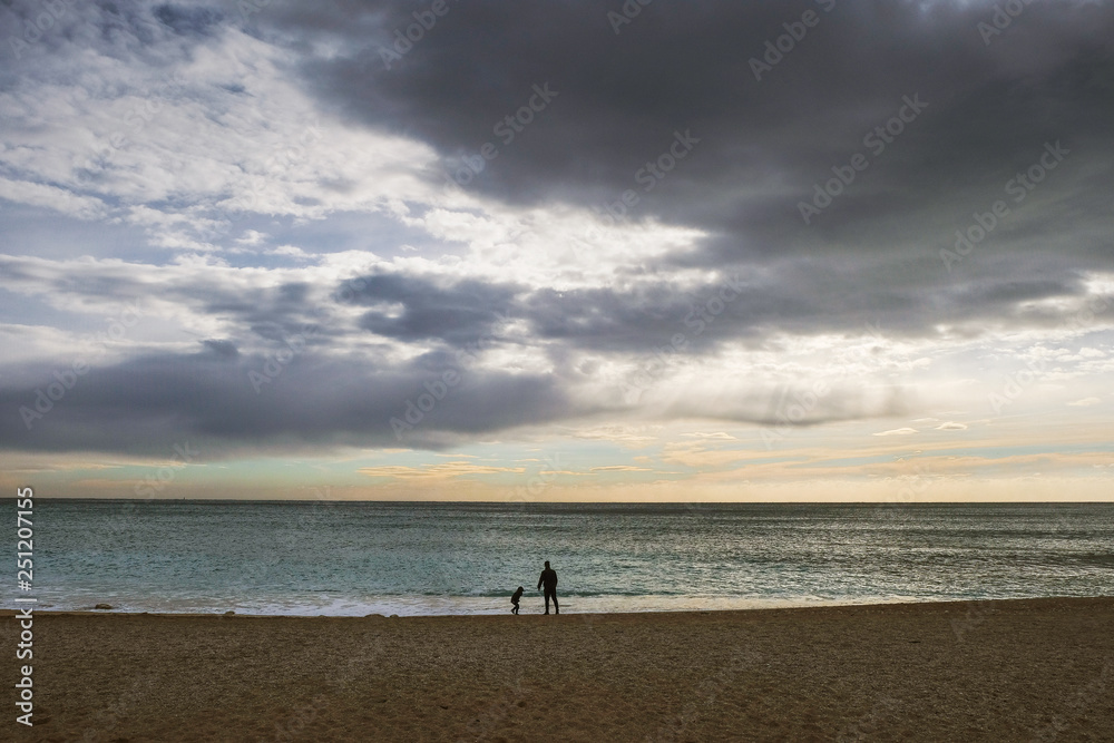 Silhouette of boy with daddy walking along the Mediterranean sea in winter. Winter tourism in Provence. Self-isolation concept. Changing the philosophy of life concept.