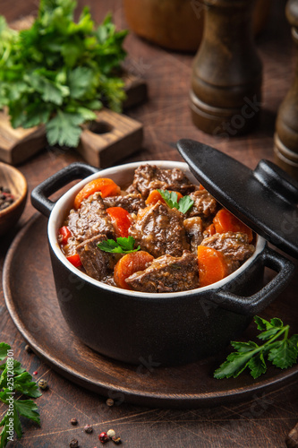 Canvastavla beef stew with vegetables in black pot on dark wooden background,