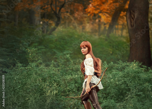 image of forest hunter, attractive girl with long red hair in white shirt and leather pants goes hunting, holds wooden bow in her hand and quiver of arrows behind her back, kitsune in human form photo