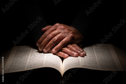 African American Man Praying with Hands on Top of the Bible