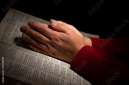 Woman Praying with Hands on Top of the Bible
