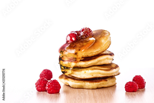 Pancakes. Homemade pancakes with raspberries and honey on a wooden board.