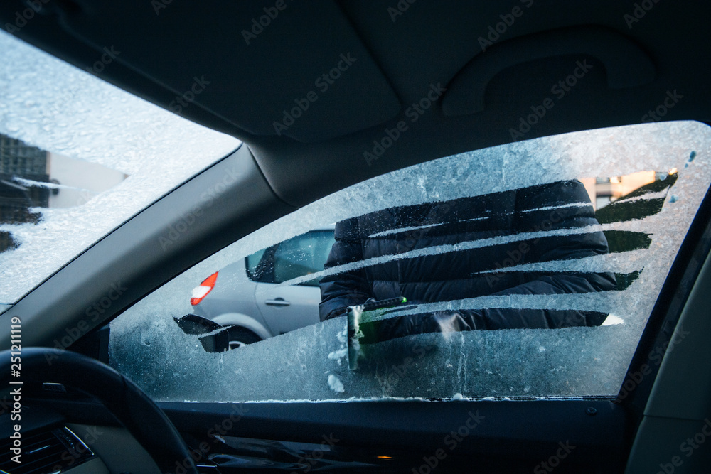 Closeup Of A Woman Using A Defrost Spray On Her Car Window Stock