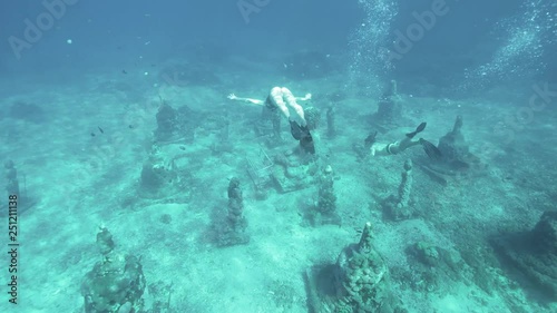 Underwater footage of some Buddha statues close to Gili Islands, Indonesia. Slowmotion shot in 4k. photo