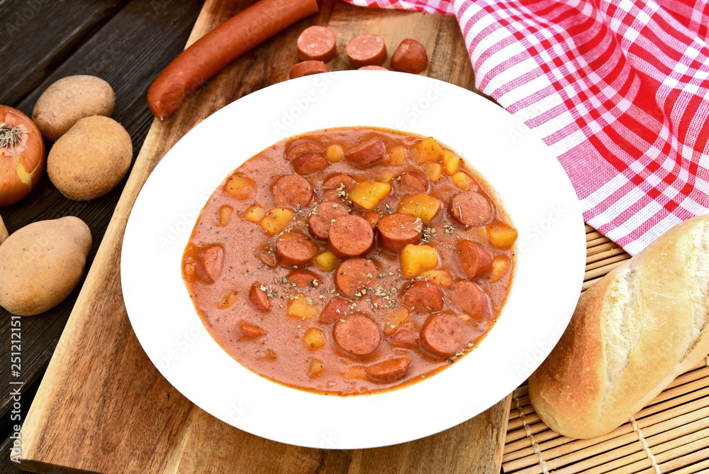 Potato goulash with Debreziner sausage or German name is Kartoffelgulasch mit Debreziner on wooden background