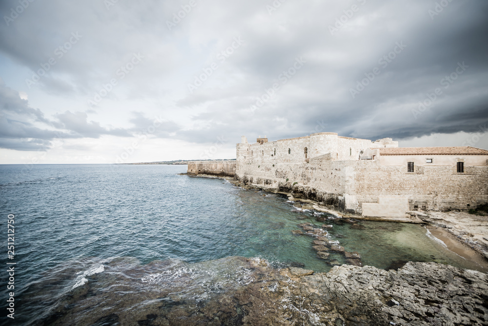 Beautiful view of Maniace castle in Ortigia Syracuse, in front of the sea and sky.