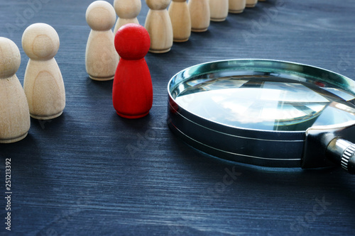 Identify concept. Recruitment and talent management. Red figurine and magnifier. photo