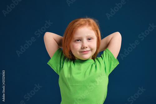 close up photo of little redhead emotional girl posing before camera on blue background