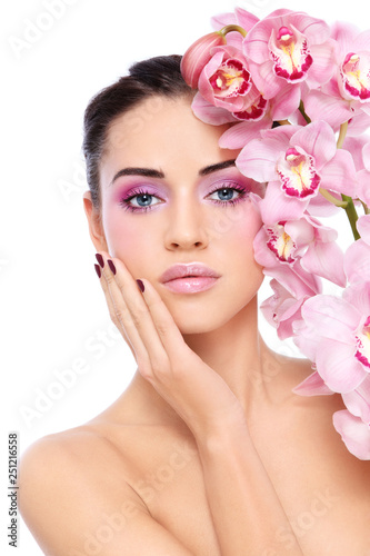 Young beautiful woman with pink make-up and orchid flower over white background