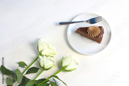 Three romance white roses and piece of chocolate cake. Compliment congradulation for women. Celebration of happy birthday, anniversary, party