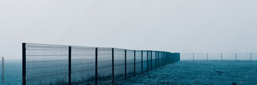 metal fence in the field, foggy morning. metal fence in the field, foggy morning.