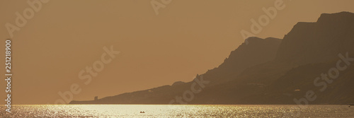 Glare on the surface of the water in the sea and mountains at sunset.