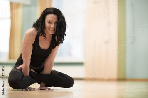 Portrait of a gorgeous mature sportswoman smiling happily practicing yoga at the gym studio copy space. Beautiful healthy cheerful woman enjoying exercising doing balance asana