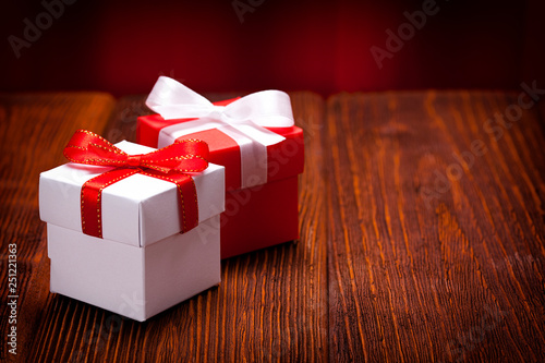 White and red gift boxes on wooden table and red curtain background