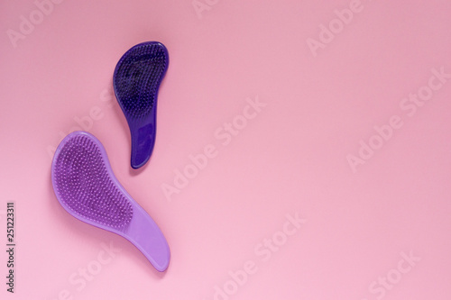 Woman make up equipment with copyspace. Plastic purple hairbrushes for combing hair on pink background. photo