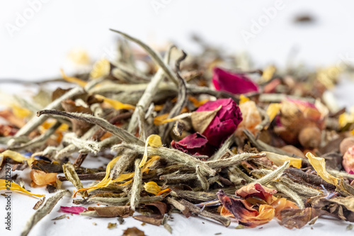 White tea with flowers, petals and rosebuds on white background. Close up of chinese white tea of premium luxury quality. Texture background macro photo. Bai Hao Yinzhen tea.