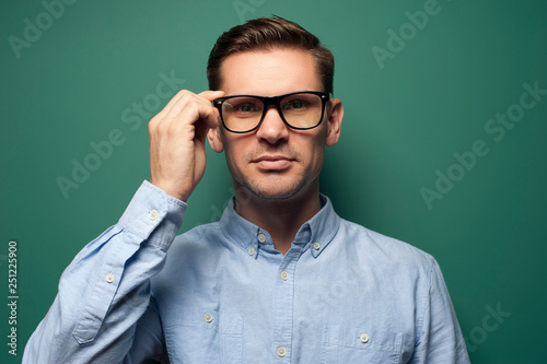 Young man businessman in a blue shirt and stylish glasses