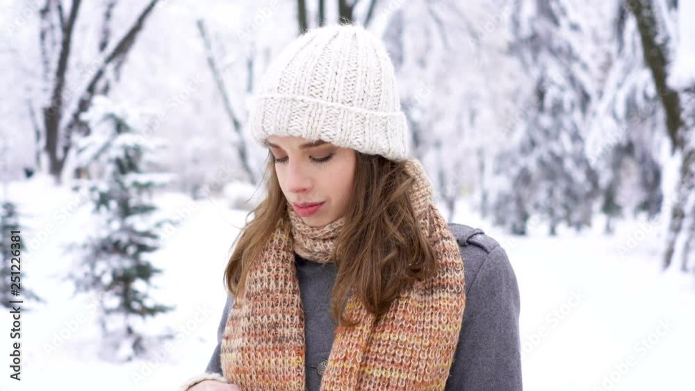 4k.Pretty young woman in in winter city park put on mittens and smile in camera. 4k.Pretty young woman in in winter city park put on mittens and smile in camera.