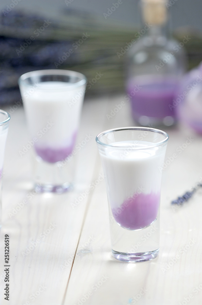 liqueur. Two glasses on a light wooden background. Close-up. Vertical frame orientation. liqueur. Two glasses on a light wooden background. Close-up. Vertical frame orientation.