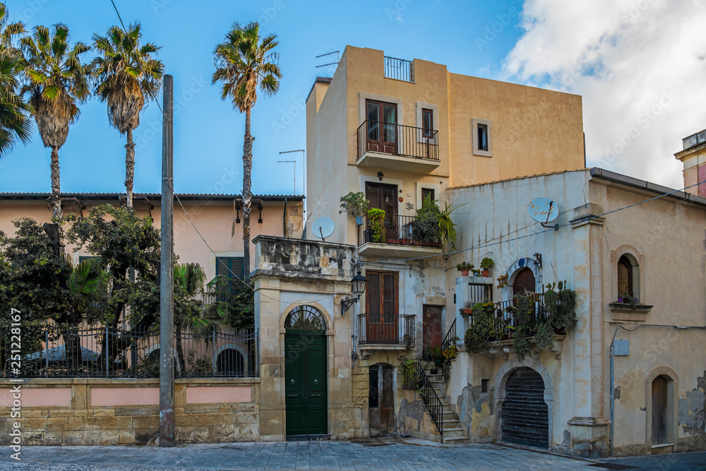 Typical italian house with greenery balconies and palm trees nearby, island Ortigia, Syracusa, Sicily, Italy