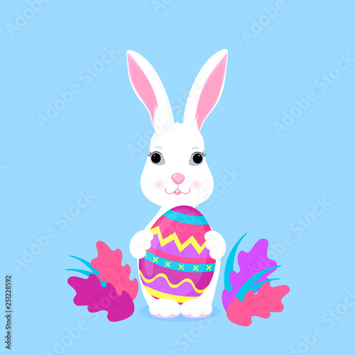Cute Easter bunny holds paschal egg in its paws.