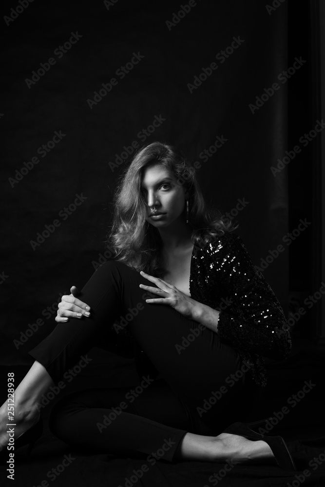 Black and white fashion photo of beautiful sexy woman with luxurious curly hair in elegant jacket with rhinestones posing in studio in front of black backgroung. Full-length girl model Black and white fashion photo of beautiful sexy woman with luxurious curly hair in elegant jacket with rhinestones posing in studio in front of black backgroung. Full-length girl model