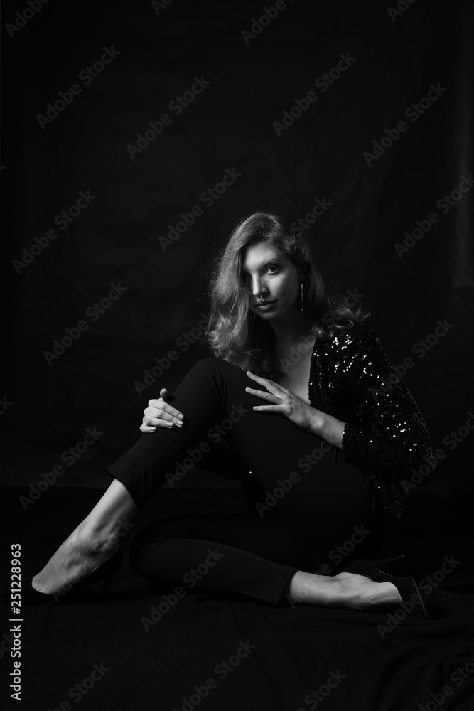 Black and white fashion photo of beautiful sexy woman with luxurious curly hair in elegant jacket with rhinestones posing in studio in front of black backgroung. Full-length girl model Black and white fashion photo of beautiful sexy woman with luxurious curly hair in elegant jacket with rhinestones posing in studio in front of black backgroung. Full-length girl model