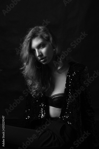 black and white fashion photo of beautiful sexy woman with luxurious curly hair in elegant jacket and lingerie posing in studio © Iulia