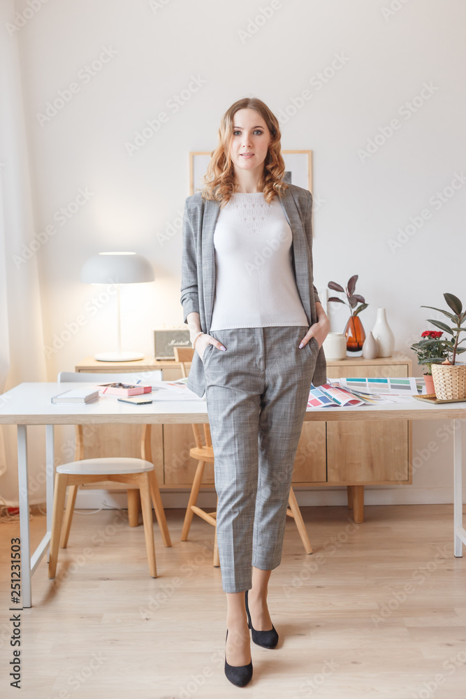 Young boss woman in a gray stylish suit stands in her own creative office Young boss woman in a gray stylish suit stands in her own creative office