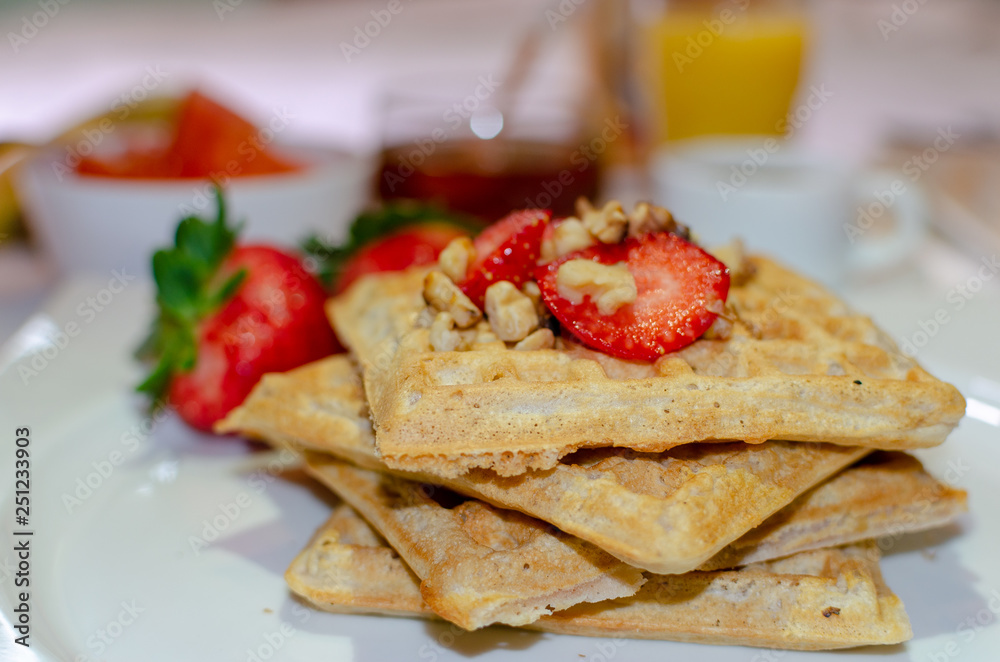 Desayuno saludable - waffles de harina del negrito, servidos con nueces, fresas, miel, jugo fresco y café
