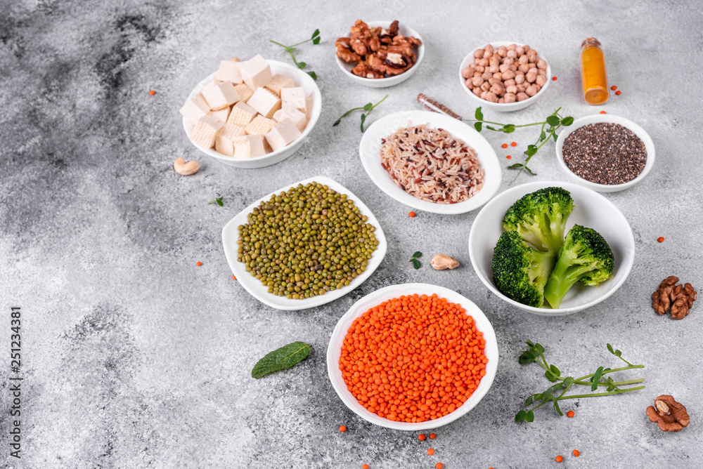 Superfoods on a gray background with copy space. Nuts, beans, greens and seeds. Healthy vegan food