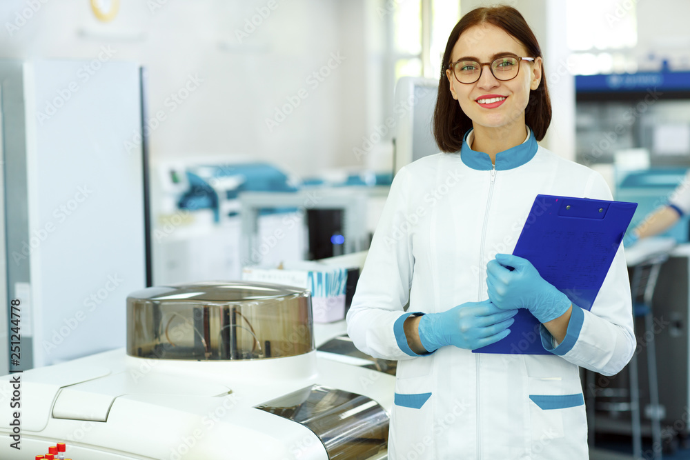 Beautiful female lab technician smiling, posing and looking at camera ...