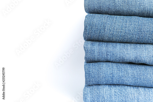 Stack of blue jeans on white background, space for text