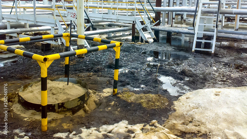 Spilled oil on sandy soil near pipelines and process equipment. Oil leaks during operation and repair. photo