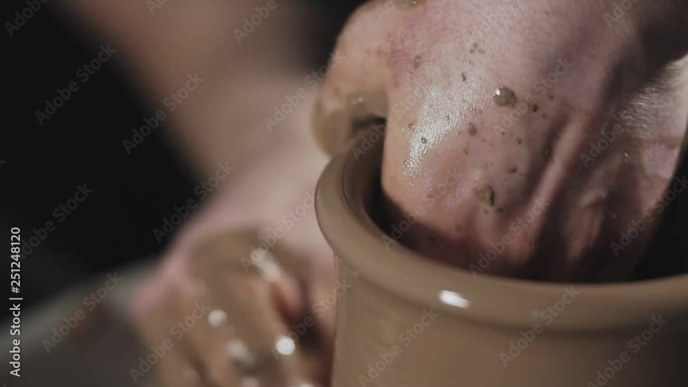 Man works with potter's wheel and clay. Processing clay ware. Ceramics of handwork and clay ware on potter's wheel. Close up view of hands Man works with potter's wheel and clay. Processing clay ware. Ceramics of handwork and clay ware on potter's wheel. Close up view of hands