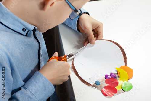 Praca plastyczna wykonywana przez dziecko. Ch  opiec wycina no  yczkami do papieru.