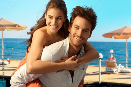 Happy couple playing piggyback at seaside beach