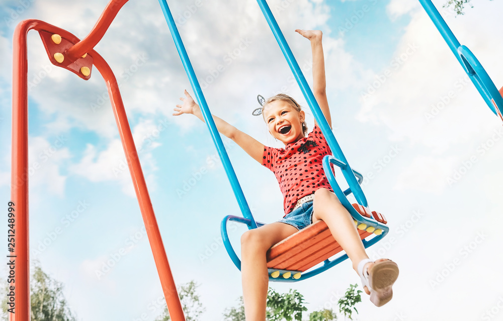Happy smiling cute little girl have fun when swing on swing