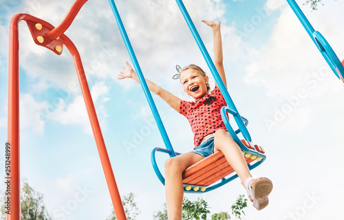 Happy smiling cute little girl have fun when swing on swing