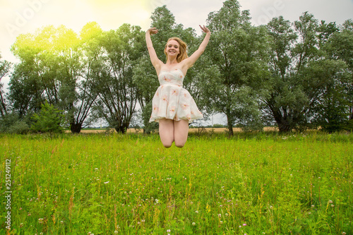 Eine junge hübsche Frau springt auf einer Wiese in die Luft