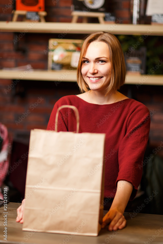 Photo of happy girl seller with paper bag Photo of happy girl seller with paper bag