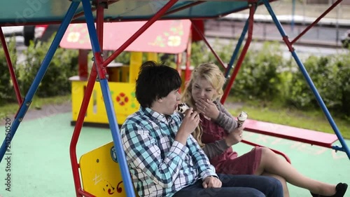 Young lovely couple at swings eating ice creama nd have fun at cloudy weather photo