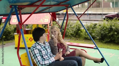 Young lovely couple at swings eating ice creama nd have fun at cloudy weather photo