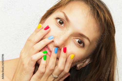 Portrait of a girl with hands and a multi-colored manicure.