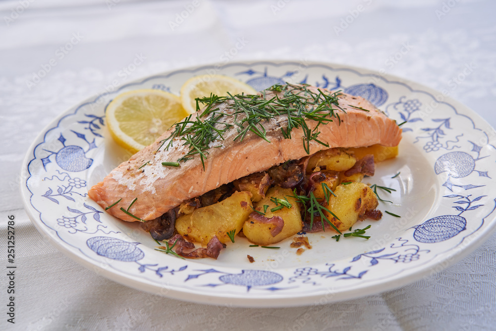 Close up picture on salmon fillet served with roasted potatoes and onion, slices of fresh lemon and chopped fresh dill on the rustic plate. Fresh, healthy, light, diet fish dish for lunch or dinner. Close up picture on salmon fillet served with roasted potatoes and onion, slices of fresh lemon and chopped fresh dill on the rustic plate. Fresh, healthy, light, diet fish dish for lunch or dinner.