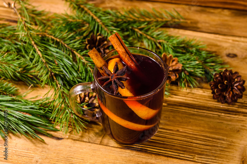 Cup of mulled wine with cinnamon and fir tree branches on wooden table